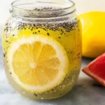 A glass jar filled with chia water infused with lemon and lime slices.